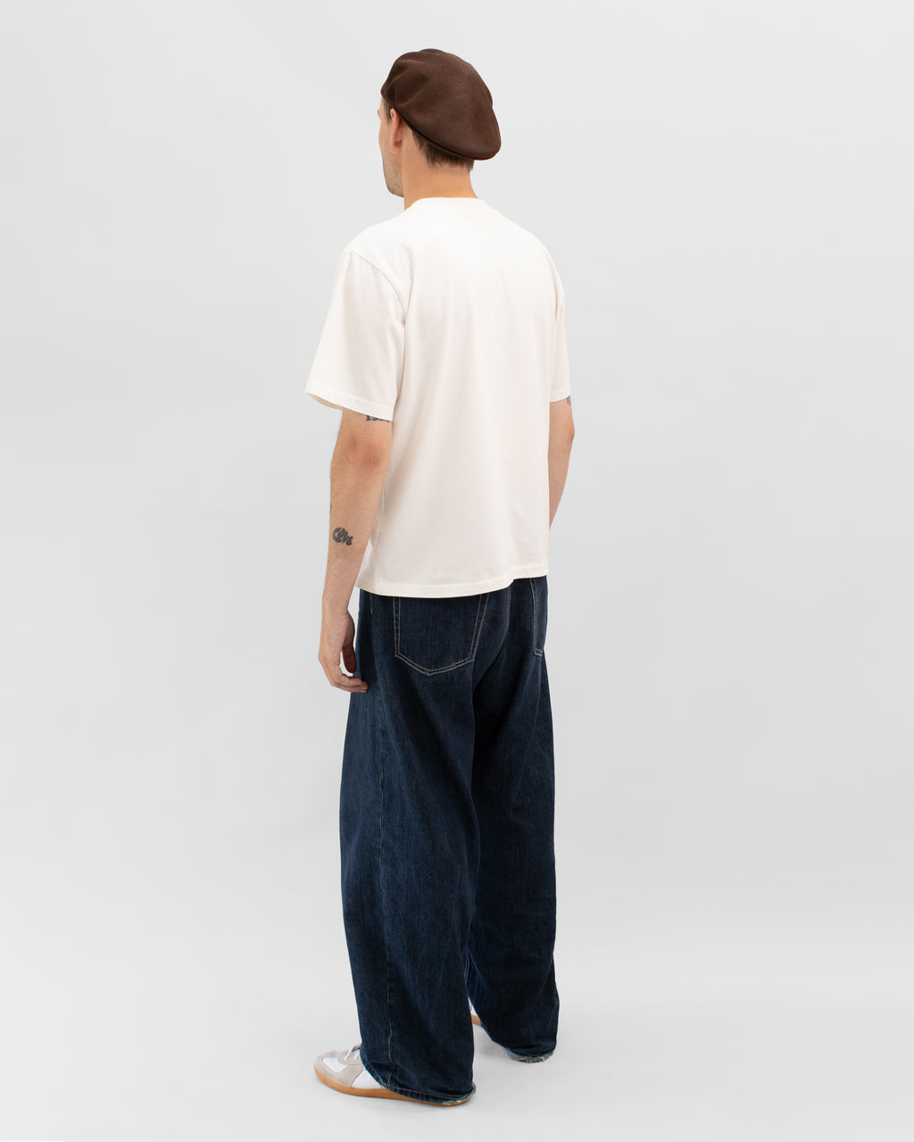 Model wearing Braddyll statement tee in white with cropped fit, french seam and single stitching seen from the back