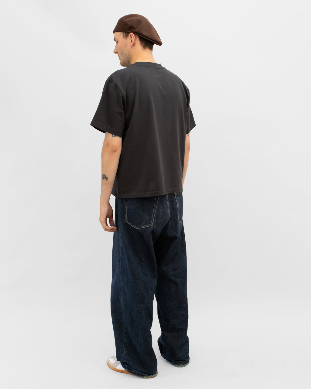 Model wearing Braddyll statement in black tee with cropped fit, french seam and single stitching seen from behind